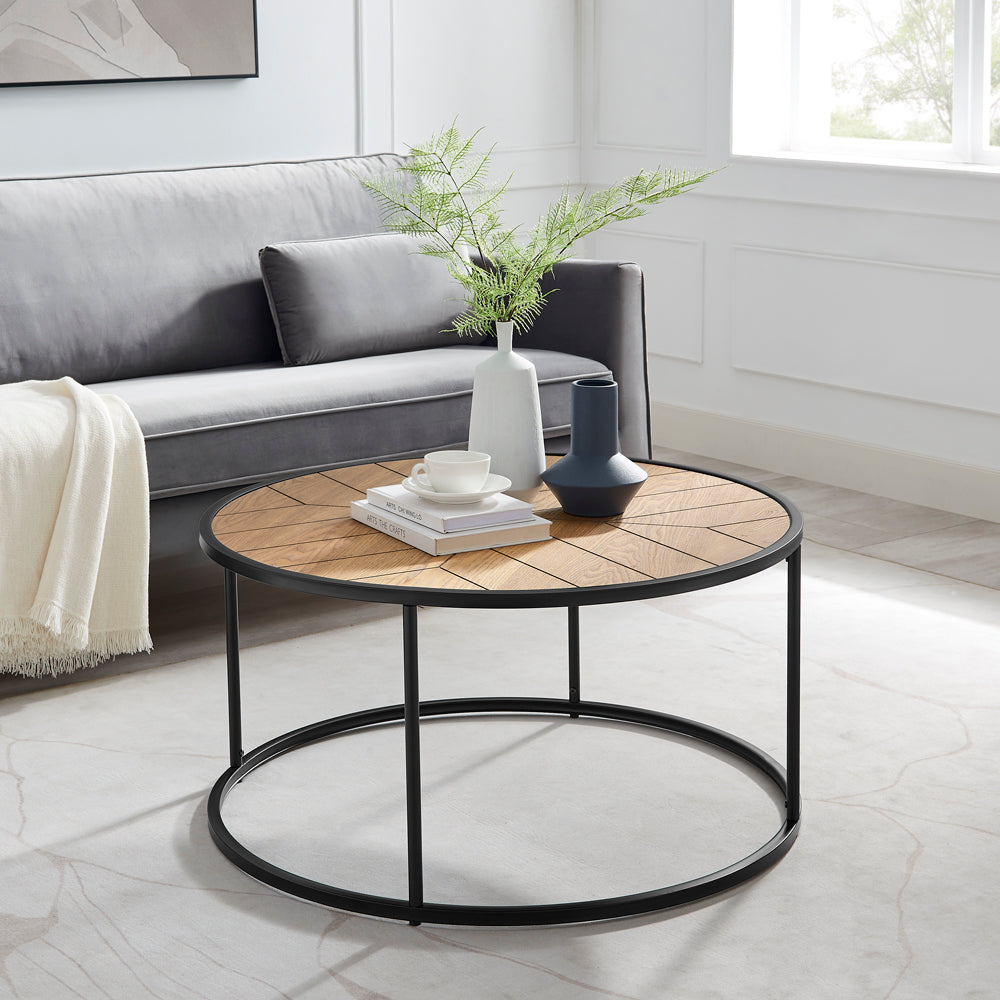 Round wooden coffee table with black metal frame in a living room setting.