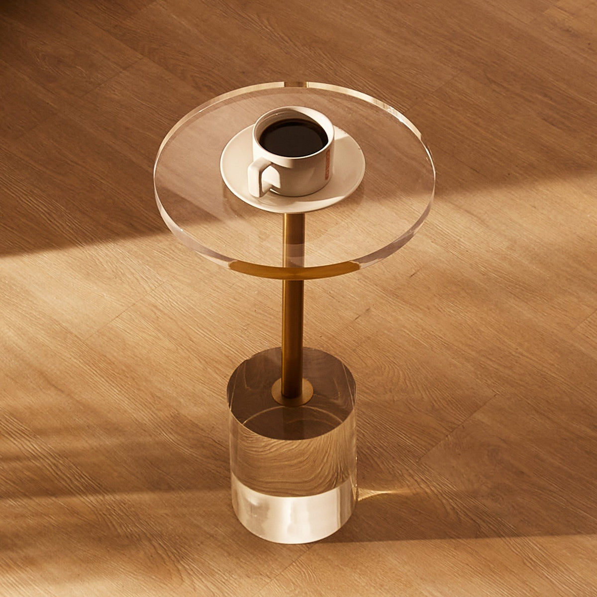 Clear glass side table with a coffee cup on a wooden floor