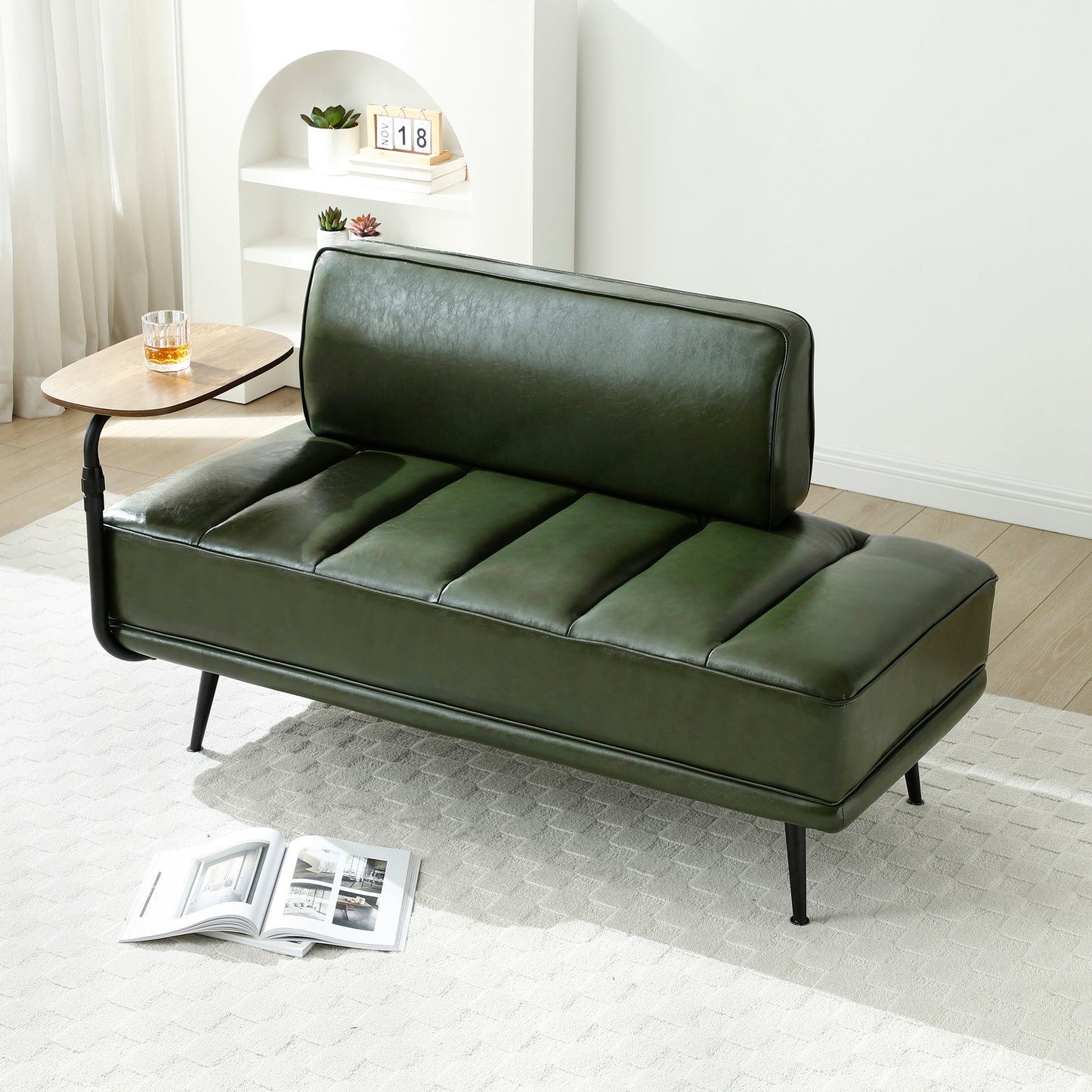 Green leather sofa in a modern living room setting with a small table and decor items.
