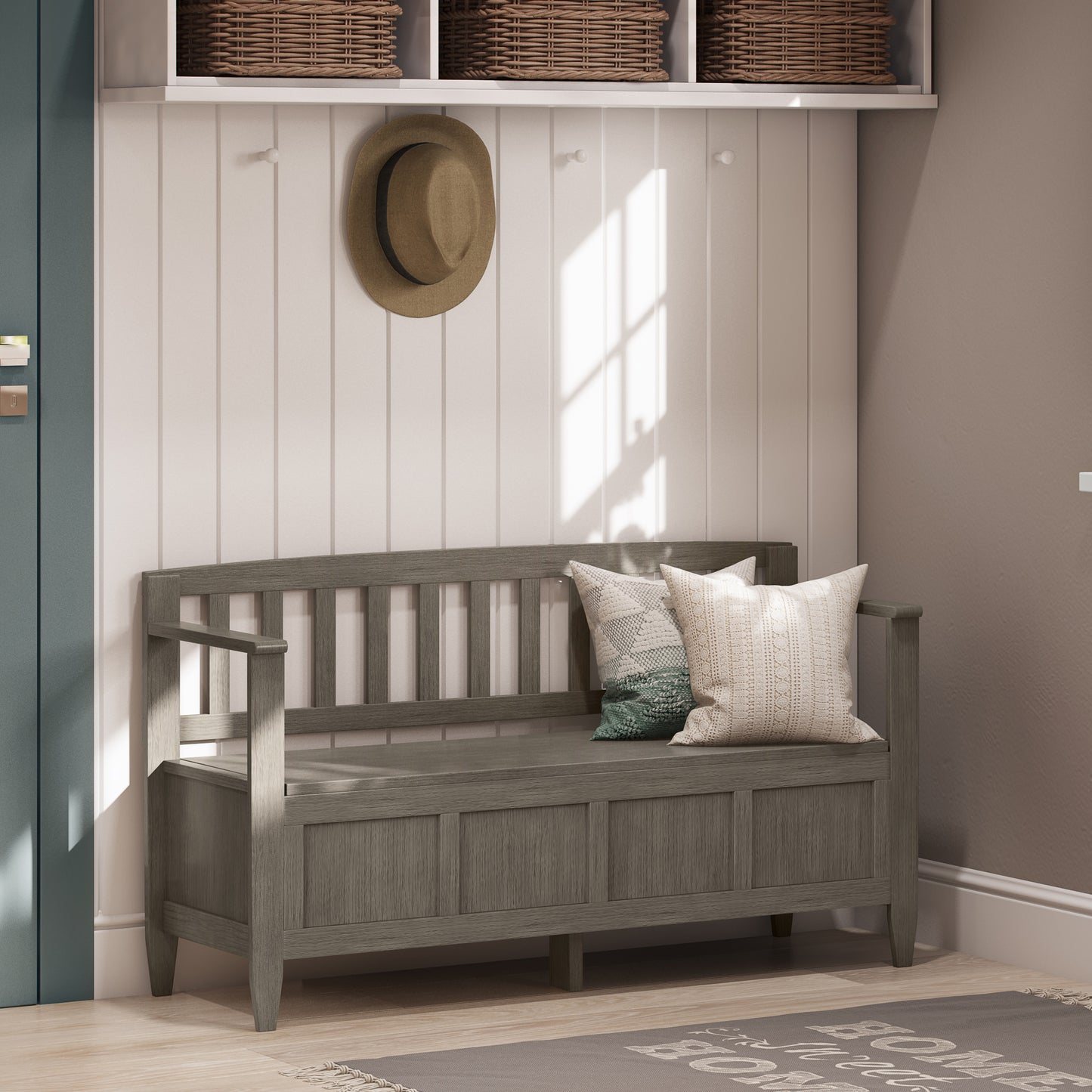 Wooden bench with cushions in a room with a hat and baskets on the wall.